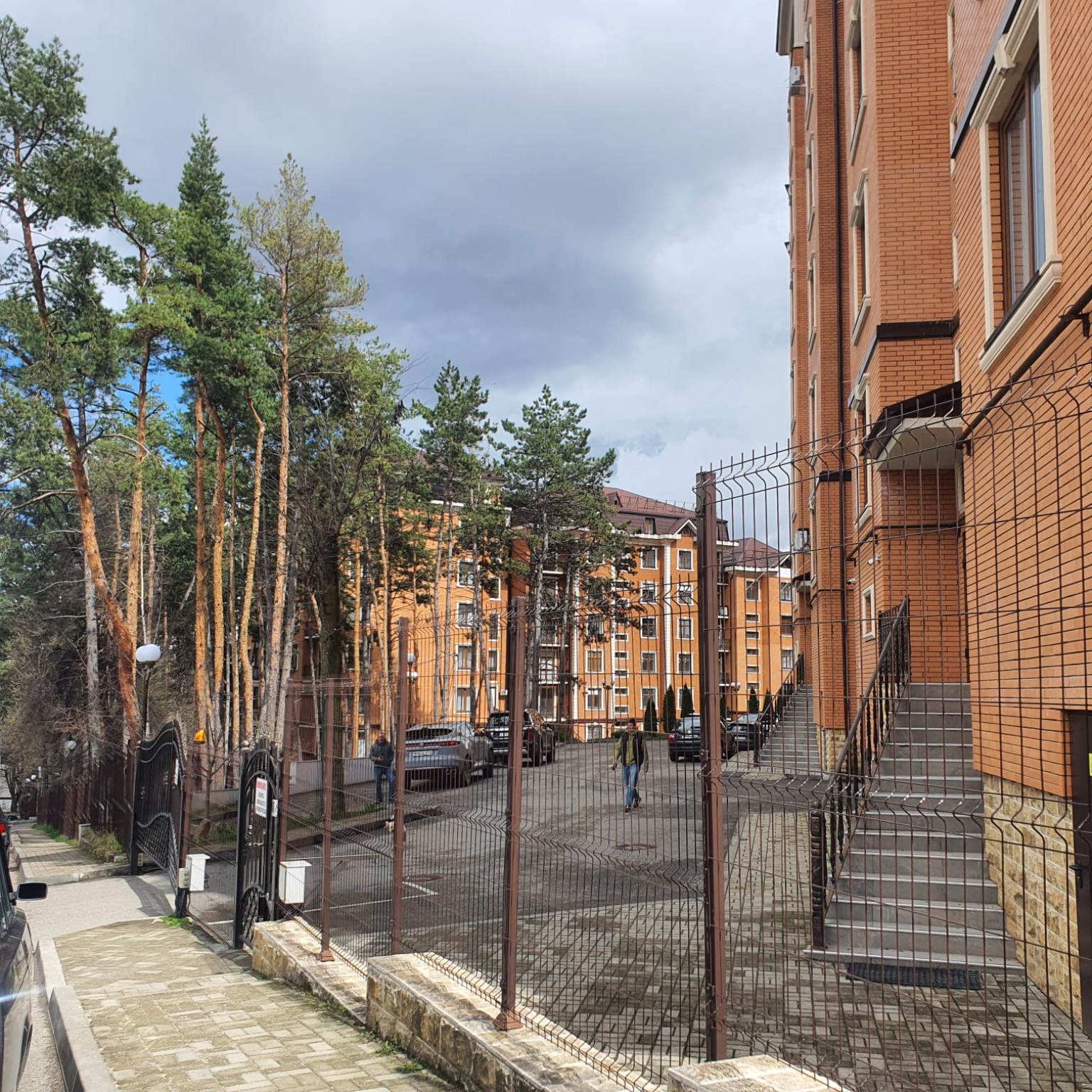 Кирпичные фасады, сосны и ограждённая территория дома